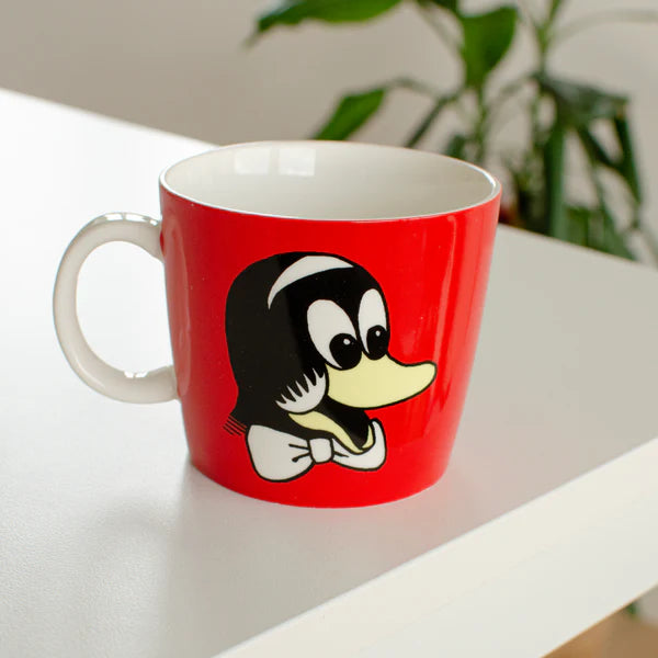 Rasmus Klump krus fra Barbo Toys med Pelle-motiv på rød baggrund, vist i et moderne hjemmemiljø. Børnevenligt krus til kakao, te og saft.