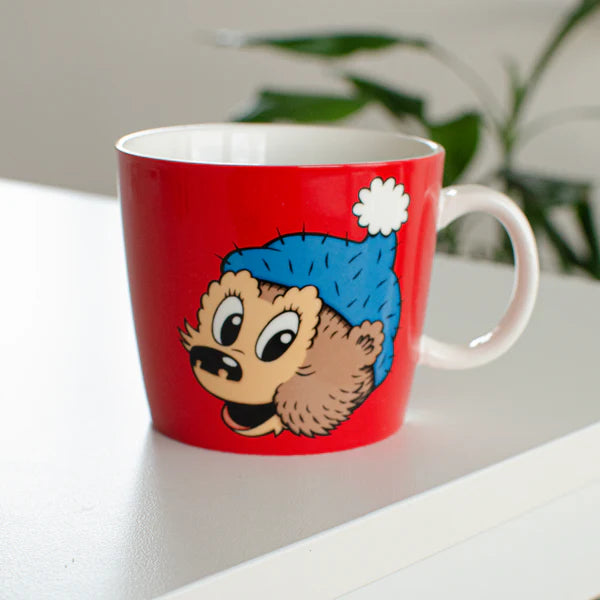 Rasmus Klump krus fra Barbo Toys med Pingo-motiv på rød baggrund, vist i et moderne hjemmemiljø. Børnevenligt krus til kakao, te og saft.